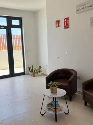 a waiting room with a chair and a table at JoLi Beach Apartments with Shared Pool in Santa Maria