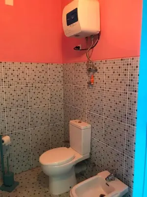 a bathroom with a toilet and a camera on the wall at Djabraba's Hiker's Suite in Garça