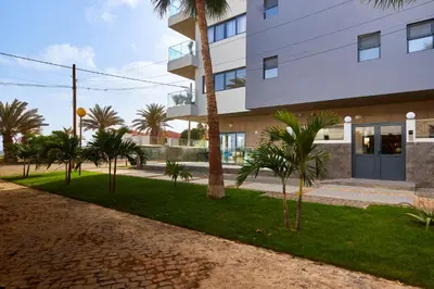 a building with palm trees in front of it at Sal Sol & Mar - Flor de Sal in Santa Maria