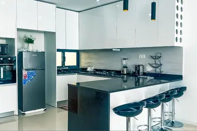 a kitchen with white cabinets and a black counter with stools at Prestige Apartment in Praia