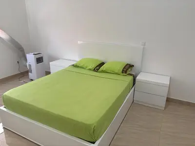 a white bedroom with a bed with green sheets and pillows at Apartamento Teixeira 2 in Espargos
