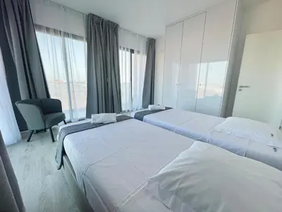 two beds in a room with a chair and windows at T1 panorâmico no Medsal Residence in Santa Maria