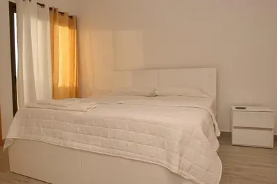 a white bedroom with a white bed with a blanket at Comfort and Peace in Santa Maria