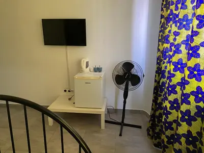 a room with a fan and a table with a television at une chambre dépaysante in Tarrafal