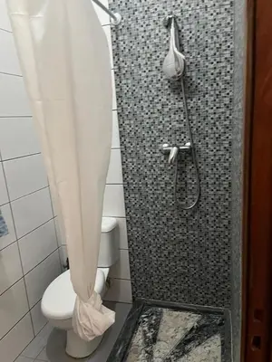 a bathroom with a shower with a toilet and a shower curtain at une chambre dépaysante in Tarrafal