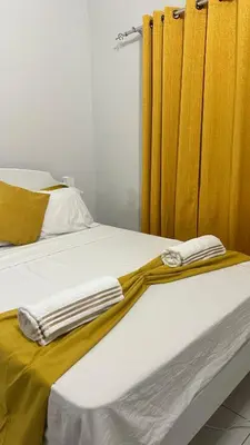 two beds with yellow curtains in a bedroom at T2 Vacation in Mindelo in Mindelo