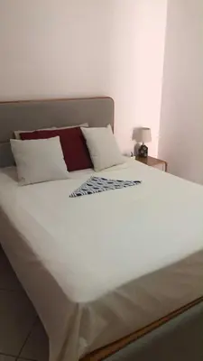 a large bed with white sheets and pillows on it at Condominio atlantico ll in Praia