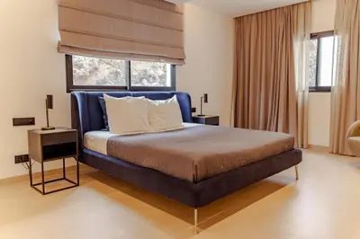 a bedroom with a bed with a blue headboard and a window at Nusa Apartments Monte Cara in Mindelo