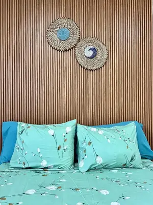a bed with two blue pillows in front of a wall at Salinas Breeze in Santa Maria