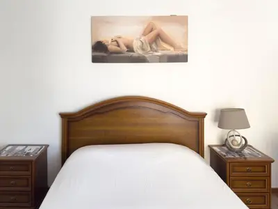 a bedroom with a bed and two night stands and a painting at Spacious 3-bdr apt seafront, exterior pool - LCGR in Praia