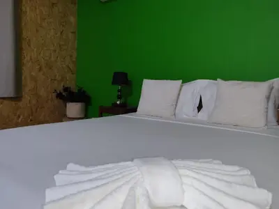 a white bed with white pillows and a green wall at Residencial P&P in Mindelo