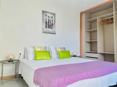 a bedroom with a large bed with green and purple pillows at Sal Little Heart Sun NEW Apartment 5 in Santa Maria