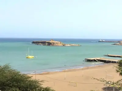 a beach with a yellow boat in the water at Maison Praia - Cap Vert in São Filipe