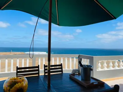 a table with an umbrella on a balcony with the beach at Residencial Sol Point Art in Ponta do Sol