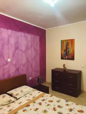 a bedroom with a bed and a purple wall at Tropical Breeze Holidays in Santa Maria