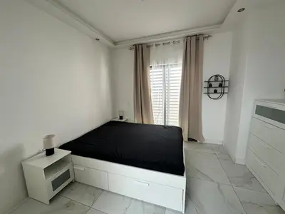 a white bedroom with a bed and a window at Belle maison Cosy et Moderne in Praia