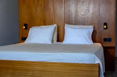 a bed with two white pillows and a wooden wall at Casa Vinti9 in Mindelo