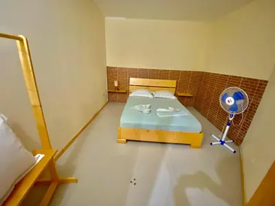 a small room with a bed and a fan at Pensão Twins Carioca in Tarrafal