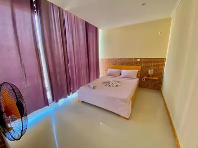 a bedroom with a bed and a fan in it at Pensão Twins Carioca in Tarrafal