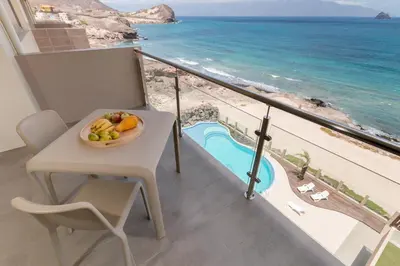 a bowl of fruit on a table on a balcony overlooking the ocean at Las Rochas Mindelo Aparthotel in Mindelo