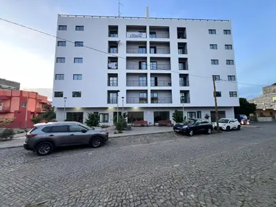 two cars parked in front of a white building at Shared Room with Balcony in Praia 5 Minute Walk to Beach in Praia