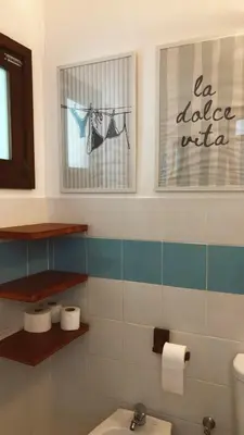 a bathroom with a toilet and two pictures on the wall at Verdes Anos - local accommodation in Santa Maria in Santa Maria