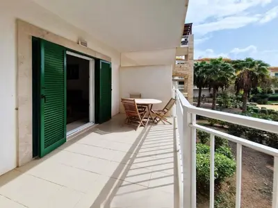 a balcony with green doors and a table and chairs at 1 bedroom apartment in Vila Verde Resort in Santa Maria