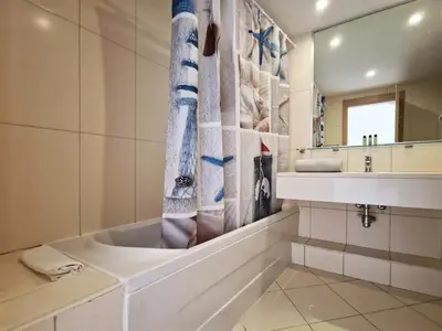 a bathroom with a tub and a sink and a mirror at 1 bedroom apartment in Vila Verde Resort in Santa Maria