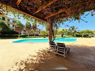 a pair of chairs sitting under an umbrella near a swimming pool at 1 bedroom apartment in Vila Verde Resort in Santa Maria