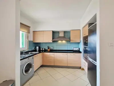 a kitchen with wooden cabinets and a washer and dryer at 1 bedroom apartment in Vila Verde Resort in Santa Maria