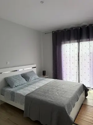 a white bedroom with a large bed and a window at Spacious apartment in Praia Great for families in Montagarro
