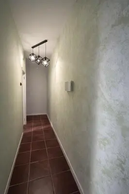 a hallway with a white wall and a tile floor at Djeu Guest House in Santa Maria