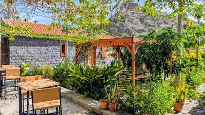 a patio with tables and chairs and a pergola at Nos Kaza in Cidade Velha