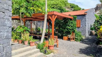 a wooden pergola with a picnic table and some plants at Nos Kaza in Cidade Velha