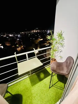 a balcony with a chair and a table and a city at Bright Modern Apart Mountain View, 5 Min to Beach in Praia
