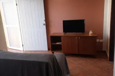 a bedroom with a television on a dresser and a door at Maio Sweet Tartaruga in Vila do Maio