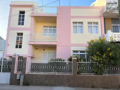 a pink house with a fence in front of it at Casa Fernandes in Praia