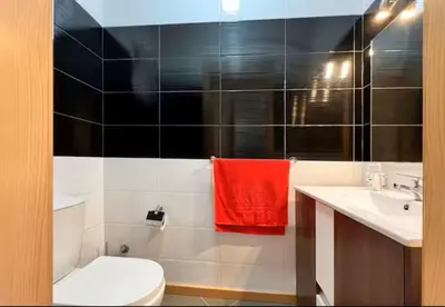 a bathroom with a white toilet and a red towel at Apartamento Vieira in Santa Maria