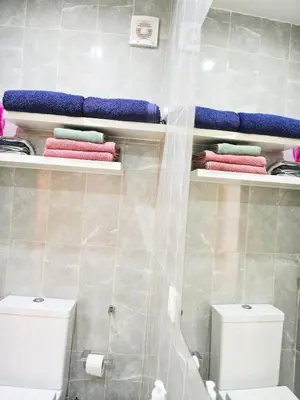a bathroom with a toilet and towels on shelves at Feeling Santa Maria in Santa Maria