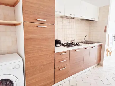 a kitchen with wooden cabinets and a washer and dryer at Apart T2 em frente à Praia - Centro de Santa Maria in Santa Maria
