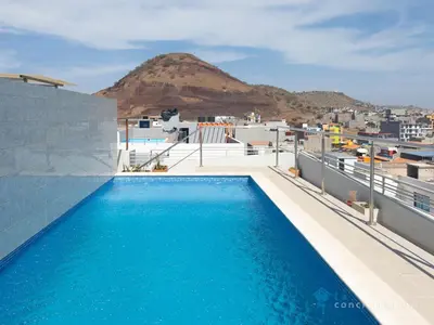 a swimming pool on the roof of a building with a mountain at Cozy 2 bdr aprt, rooftop pool - LCGR in Praia
