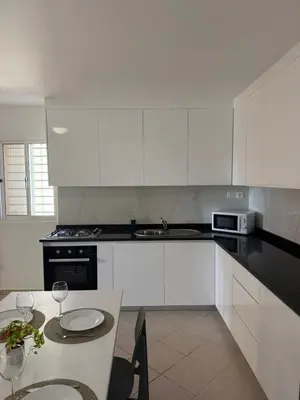 a kitchen with white cabinets and a table with wine glasses at Estrela do Sul Santa Maria by RPG Group in Santa Maria