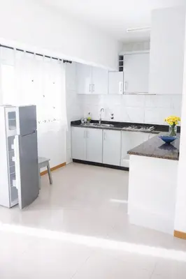 a white kitchen with white cabinets and a refrigerator at Ti Jona Rooms in Mindelo