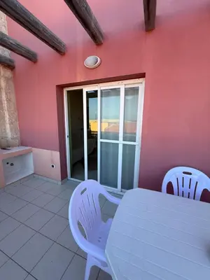 a table and chairs in a room with a pink wall at Apartament POR DO SOL A9 praia Cabral wi-fi free Sal Rei in Sal Rei