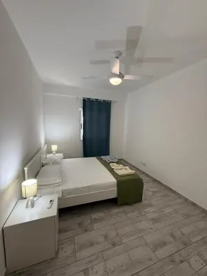 a white bedroom with a bed and a night stand at Apartament ROSA DEI VENTI 3D Estoril Sal Rei in Sal Rei