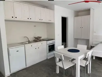 a kitchen with white cabinets and a table and chairs at Modern Flat in Mindelo - 3B in Mindelo