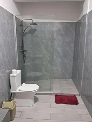 a bathroom with a shower with a toilet and a red rug at Apartment T3 located Rua 4 de Julho Sal Rei blv in Sal Rei
