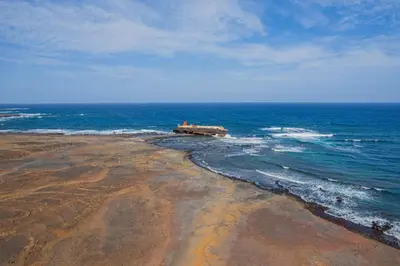 a beach with a building in the middle of the ocean at Hospedaria Santo António