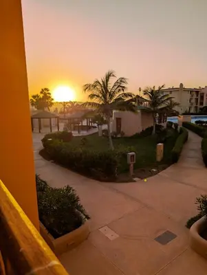a sunset over a courtyard with palm trees and buildings at SUNSENT GLOW - Tropical Apt N11 - PointingCaboVerde in Santa Maria