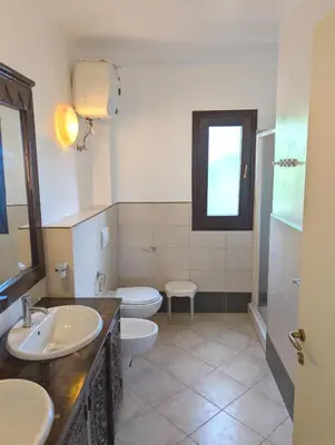 a bathroom with two sinks and a toilet and a window at SUNSENT GLOW - Tropical Apt N11 - PointingCaboVerde in Santa Maria